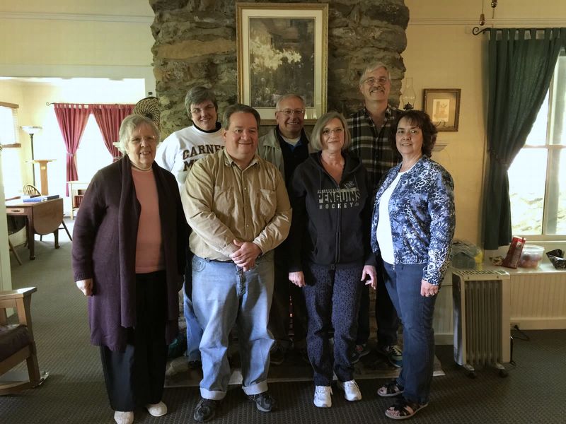 Seven members of the Cottrell Seminar standing together before a stone fireplace
