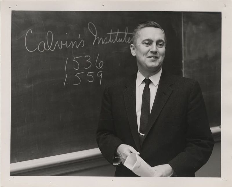 Dr. Leith at a chalkboard on which is written Calvin’s Institutes, 1536, 1559