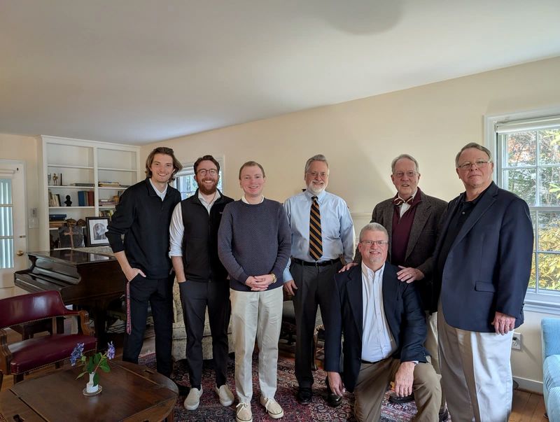 Seven members of a seminar together in a living room, one kneeling in front
